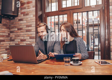 Business couple having discussion about job, while sitting in cafe.Happy colleagues having video call with laptop during the coffee break. Stock Photo