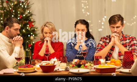 friends praying before christmas dinner at home  Stock Photo