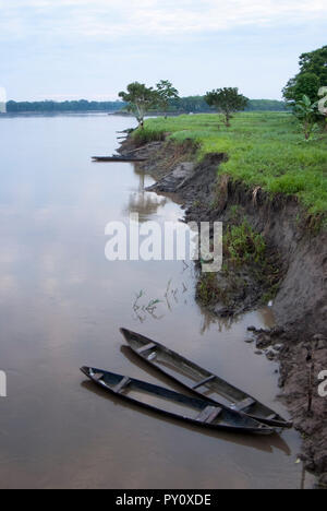 Two traditional wooden canoes at sunset in the Amazon River basin with tropical rainforest, Iquitos.