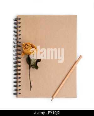 dried rose flower with pencil on notebook page Stock Photo