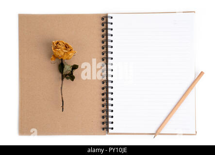 dried rose flower with pencil on notebook page Stock Photo