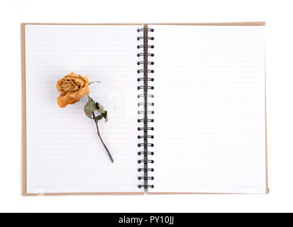 dried rose flower with pencil on notebook page Stock Photo