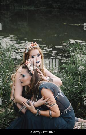 Two boho women sitting by a lake, Russia Stock Photo