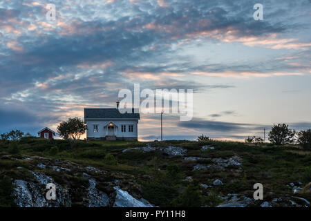 A lonely house standing on a hill against the backdrop of clouds lit by the setting sun Norway. Hitra August 2018 Stock Photo