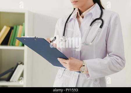 cropped view of female doctor writing diagnosis in clipboard Stock Photo