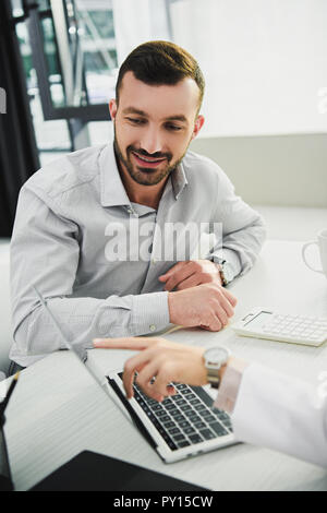 doctor showing something on laptop to male client in office Stock Photo