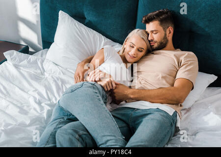 young couple hugging and sleeping on bed in bedroom Stock Photo