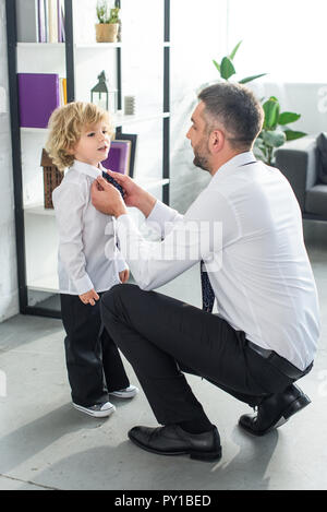 side view of father helping little son tying necktie at home Stock Photo