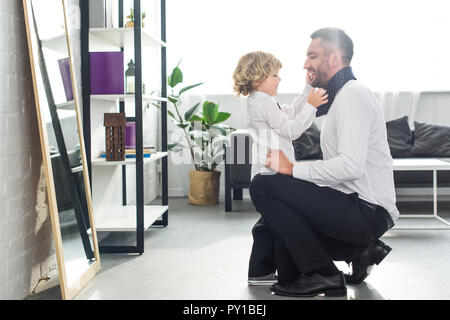 side view of little boy helping father tying necktie at home Stock Photo
