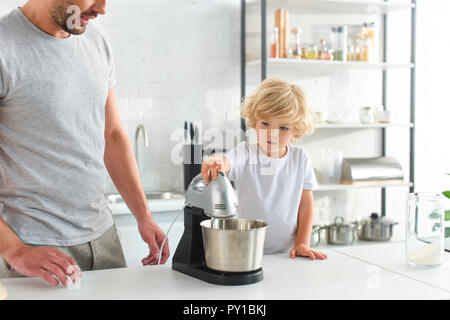 cropped image of man standing near son while he using mixer at kitchen Stock Photo