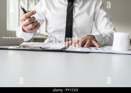 Busy financial adviser working at his business desk with many documents, charts and reports. Stock Photo