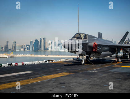 DOHA, QATAR (Oct. 14, 2018) An F-35B Lightning II, attached to the “Avengers” of Marine Fighter Attack Squadron (VMFA) 211, is chocked and chained on the flight deck as the Wasp-class amphibious assault ship USS Essex (LHD 2) arrives in Doha, Qatar. USS Essex is a flexible, and persistent Navy-Marine Corps team deployed to the U.S. 5th Fleet area of operation in support of naval operations to ensure maritime stability and security in the Central Region, connecting the Mediterranean and the Pacific through the western Indian Ocean and three strategic choke points. (U.S. Navy photo by Mass Commu Stock Photo