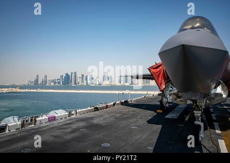 DOHA, QATAR (Oct. 14, 2018) An F-35B Lightning II, attached to the “Avengers” of Marine Fighter Attack Squadron (VMFA) 211, is chocked and chained on the flight deck as the Wasp-class amphibious assault ship USS Essex (LHD 2) arrives in Doha, Qatar. USS Essex is a flexible and persistent Navy-Marine Corps team deployed to the U.S. 5th Fleet area of operation in support of naval operations to ensure maritime stability and security in the Central Region, connecting the Mediterranean and the Pacific through the western Indian Ocean and three strategic choke points. (U.S. Navy photo by Mass Commun Stock Photo