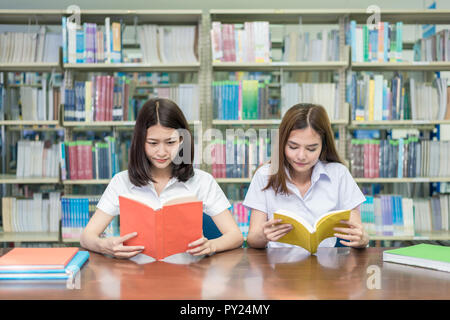 Two Asian students studying together in library at university. University student. Stock Photo