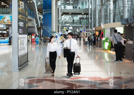 Portrait of Asian young happy couple business man and business woman with baggage walking and talking at terminal in airport. Business travel in airpo Stock Photo