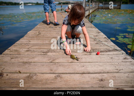 Three children fishing on a dock in the summer, United States Stock Photo