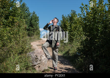 Hiker standing on a footpath talking on his mobile phone, Bosnia and Herzegovina Stock Photo
