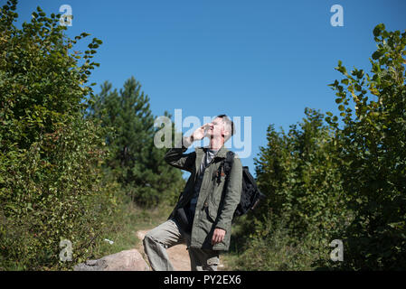 Hiker standing on a footpath talking on his mobile phone, Bosnia and Herzegovina Stock Photo
