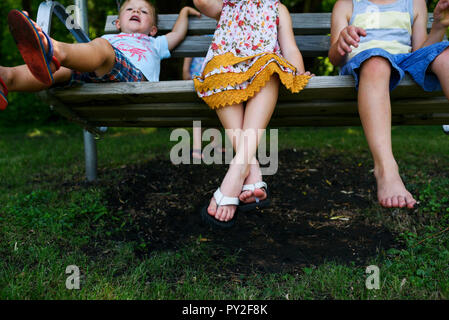 Three children sitting on a  porch swing Stock Photo