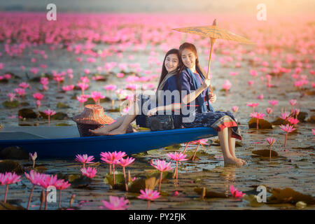 Two women sitting on a boat in a lotus flower lake, Thailand Stock Photo