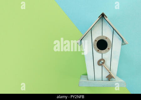 Blue wooden bird house with a metal key on a blue and green background with copy space as a concept for a new home Stock Photo
