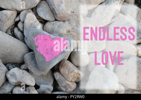 Pink heart painted with lipstick on piece of stone on background of many small stones with text letter Endless love Stock Photo