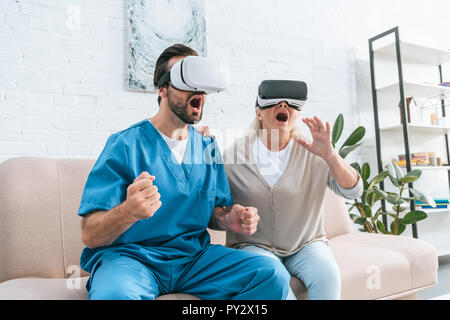 emotional social worker and excited senior woman using virtual reality headsets Stock Photo