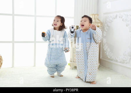 the sibings wearing baby bear sleeping bags are playing hide and seek Stock Photo