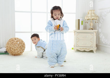 the sibings wearing baby bear sleeping bags are playing hide and seek Stock Photo