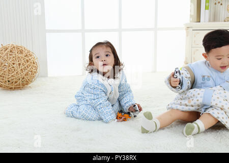 the sibings wearing baby bear sleeping bags are playing hide and seek Stock Photo