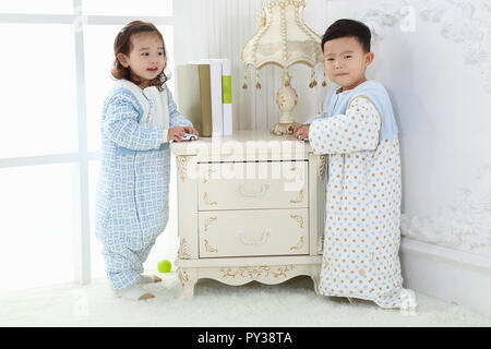 the sibings wearing baby bear sleeping bags are playing hide and seek Stock Photo