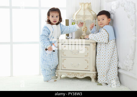 the sibings wearing baby bear sleeping bags are playing hide and seek Stock Photo