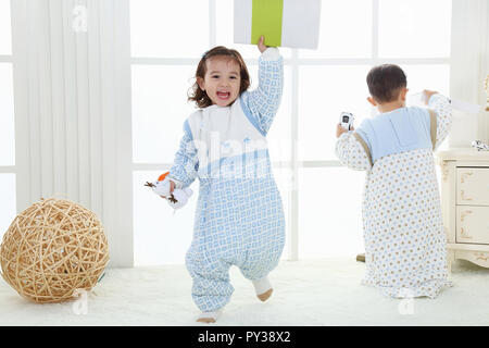 the sibings wearing baby bear sleeping bags are playing hide and seek Stock Photo