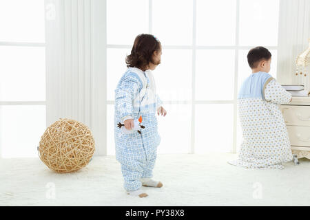 the sibings wearing baby bear sleeping bags are playing hide and seek Stock Photo