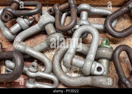A selection of shackles of various sizes on a well used workbench Stock Photo