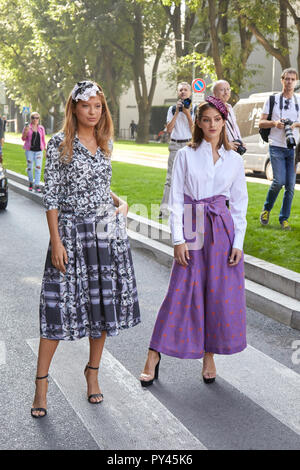 MILAN, ITALY - SEPTEMBER 23, 2018: Women with black and white dress and purple skirt before Giorgio Armani fashion show, Milan Fashion Week street sty Stock Photo