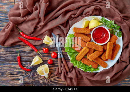 overhead view of served on a white plate with lemon, lettuce leaves and tomato sauce, horizontal view from above, flat lay Stock Photo