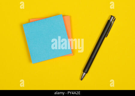 Colorful postit notes with pen on a yellow background Stock Photo