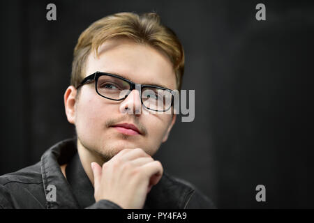 Serious young caucasian man wearing black glasses looking up and thinking Stock Photo