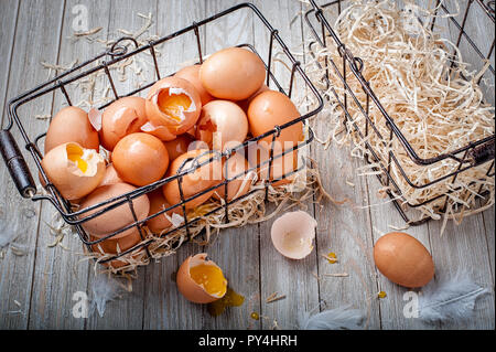 Visual metaphor/proverb: Don't put all of your eggs in one basket with cracked eggs. Stock Photo