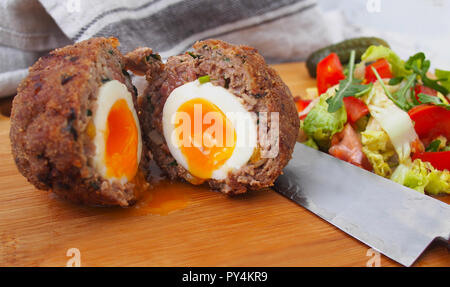 Traditional "Scotch egg" on a wooden plate. Scotch eggs and salad Stock Photo