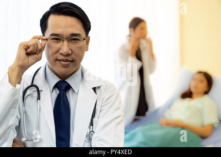 Portrait of Young adult Doctor with nurse and Patient in background. Stock Photo