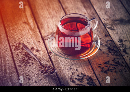 Glass cup of tea with saucer on a wooden table Stock Photo
