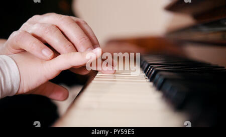 An old teacher teaching little girl how to play piano. Touching hands Stock Photo