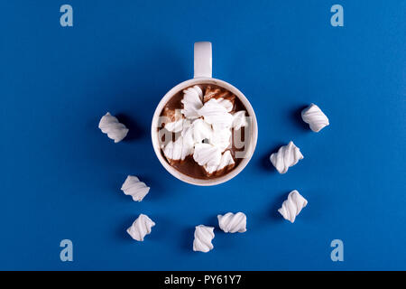 Hot chocolate with marsmallow candies on blue paper background. Top view. Copy space Stock Photo