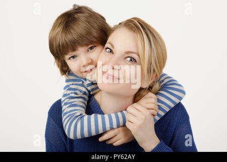 A smiling little boy and his mother hugging on the white background.  Concept of love and family. Stock Photo