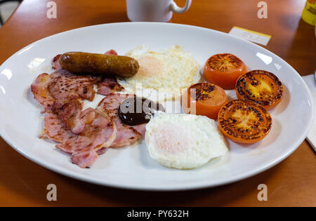 Typical traditional English breakfast of sausage bacon fried eggs and tomatoes at fat Boy cafe in New Malden Kingston Stock Photo