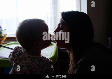 Young two year old baby toddler girl kissing her mother Stock Photo