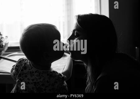 Young two year old baby toddler girl kissing her mother Stock Photo