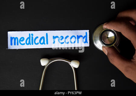 Conceptual image with Medical record inscription with the view of stethoscope, in someone hand with black background. Medical Conceptual. Stock Photo